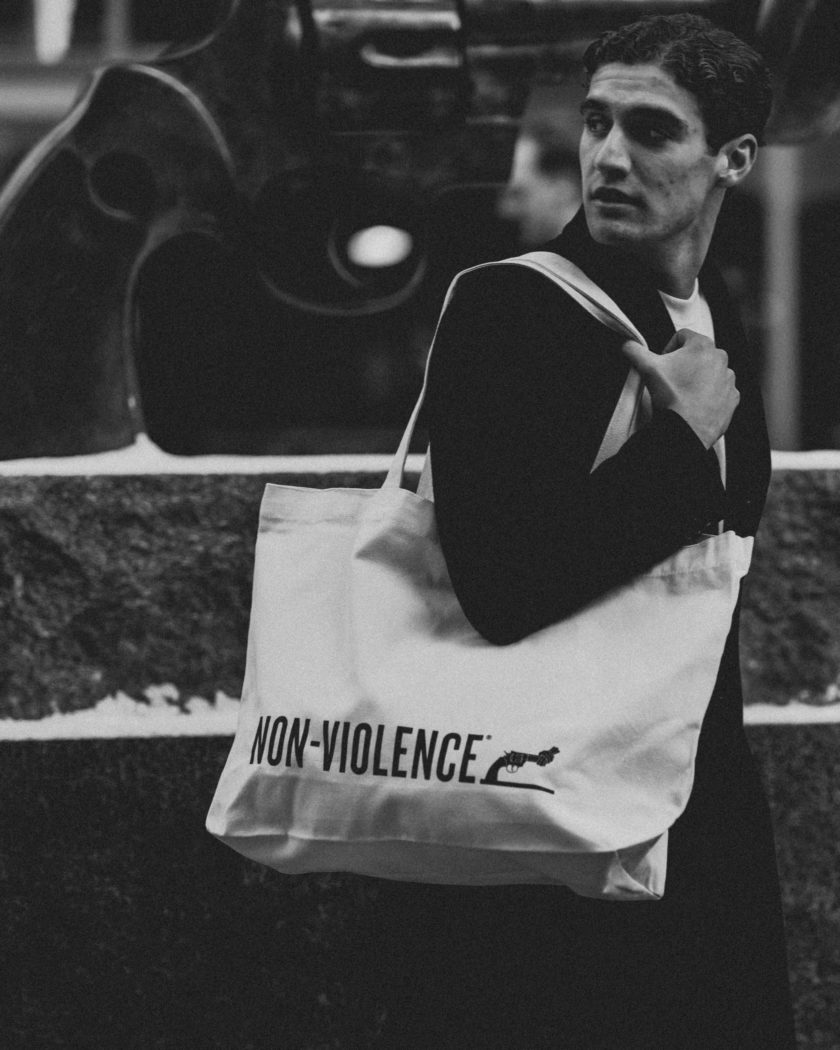 A man with a Non-Violence Tote bag designed with a Non-Violence logo on the front.