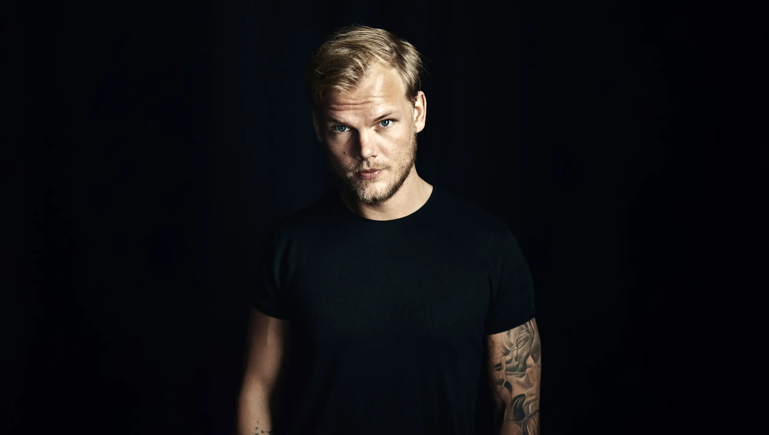 The Swedish DJ Avicii posted for a picture in a black background, a photography by Sean Eriksson and Imani McCray